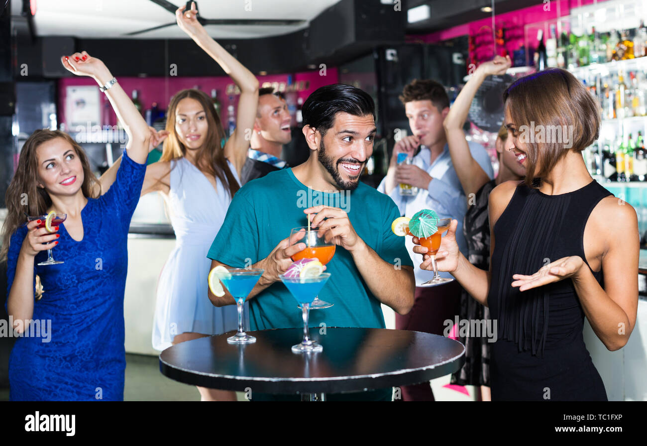 Adulto felice maschio con due femmine sono a parlare e a bere un cocktail sulla parte. Foto Stock