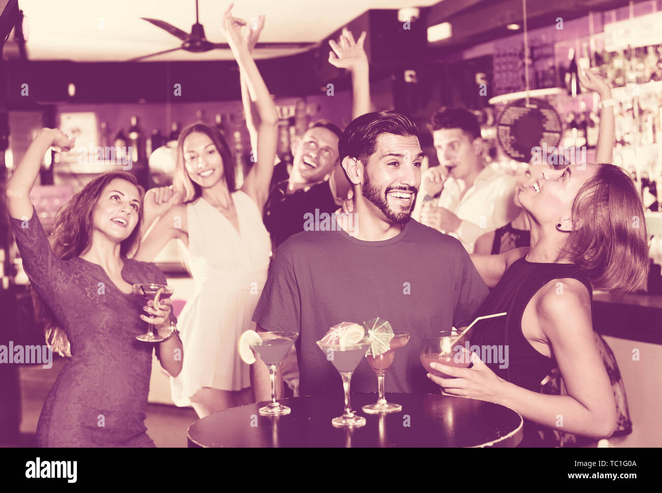 Allegro uomo sorridente con giovani donne stanno godendo il partito in bar. Foto Stock