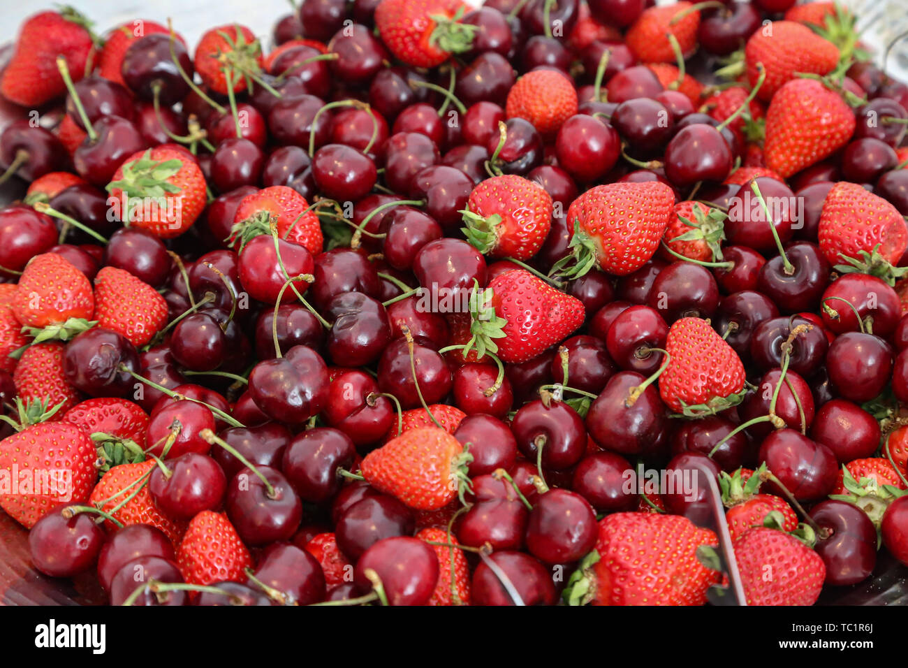 Fragole mature e ciliegie sparsi sul tavolo. Foto Stock