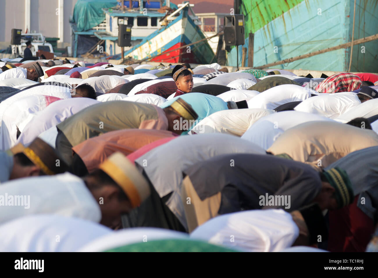 Un bambino guarda i residenti che pregare Eid al-Fitr in Il Porto di Sunda Kelapa a Jakarta. Eid al-Fitr 1440 H è una festa religiosa celebrata dai musulmani di tutto il mondo che segna la fine del Ramadan, il mese sacro del digiuno islamico. Foto Stock
