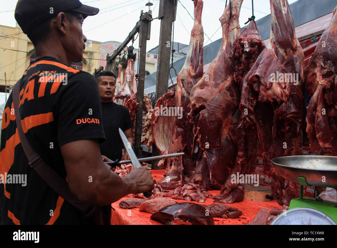 Un commerciante vende carne ad un mercato tradizionale per i musulmani durante il 'Meugang' nella tradizione Lhokseumawe. La tradizione di 'Meugang' nel senso di acquistare la carne dal mercato per la cottura è stata andando su per centinaia di anni da sotto la leadership di Sultan Iskandar Muda nell'anno 1607 al 1636. Questa tradizione è stata effettuata durante l'inserimento di Ramadan, Eid Fitri e l'Eid al-Adha ogni anno. Foto Stock