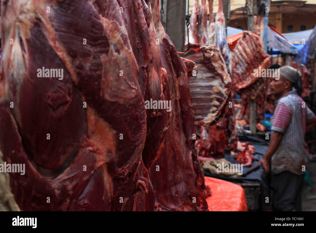 Un commerciante vende carne ad un mercato tradizionale per i musulmani durante il 'Meugang' nella tradizione Lhokseumawe. La tradizione di 'Meugang' nel senso di acquistare la carne dal mercato per la cottura è stata andando su per centinaia di anni da sotto la leadership di Sultan Iskandar Muda nell'anno 1607 al 1636. Questa tradizione è stata effettuata durante l'inserimento di Ramadan, Eid Fitri e l'Eid al-Adha ogni anno. Foto Stock