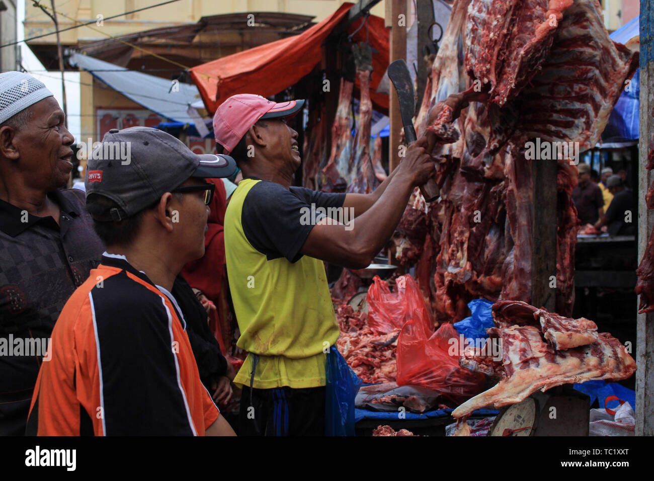 Un commerciante vende carne ad un mercato tradizionale per i musulmani durante il 'Meugang' nella tradizione Lhokseumawe. La tradizione di 'Meugang' nel senso di acquistare la carne dal mercato per la cottura è stata andando su per centinaia di anni da sotto la leadership di Sultan Iskandar Muda nell'anno 1607 al 1636. Questa tradizione è stata effettuata durante l'inserimento di Ramadan, Eid Fitri e l'Eid al-Adha ogni anno. Foto Stock