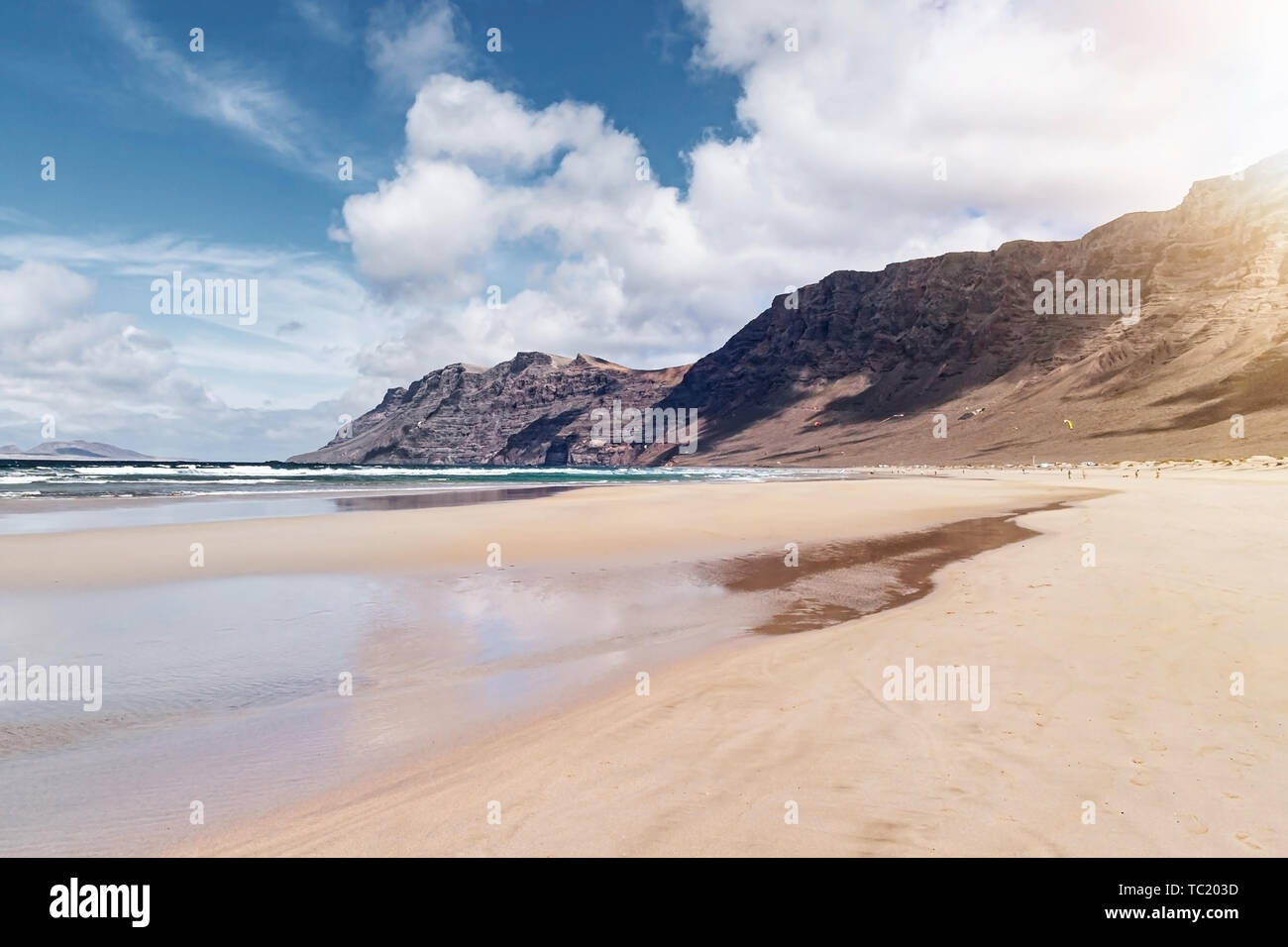 Ampia di sabbia spiaggia di Famara a Lanzarote, Spagna contro oceano Atlantico, montagne scoscese e bellissimo cielo Foto Stock