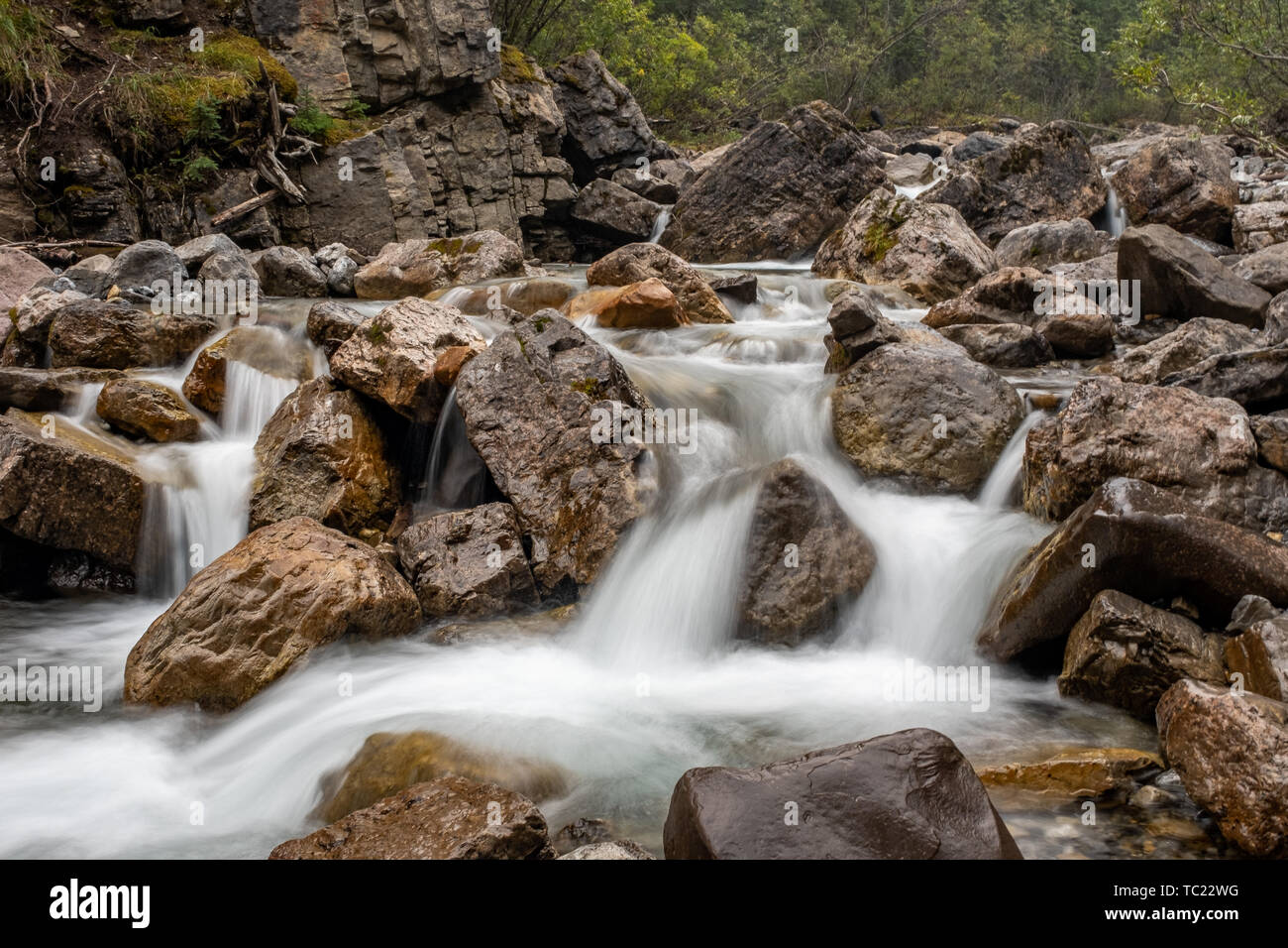 Una cascata di torrente di montagna si piega e si insinua intorno rocce e massi, lunga esposizione per creare la sfocatura in movimento per l'acqua, nessuno nell'immagine Foto Stock