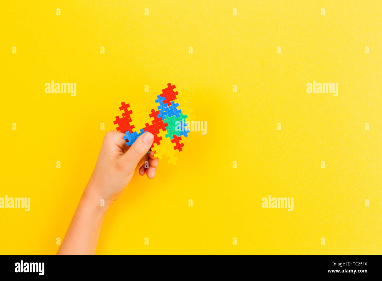 Kid mano azienda cuore colorati su sfondo giallo. Mondo autismo consapevolezza giorno di concetto Foto Stock