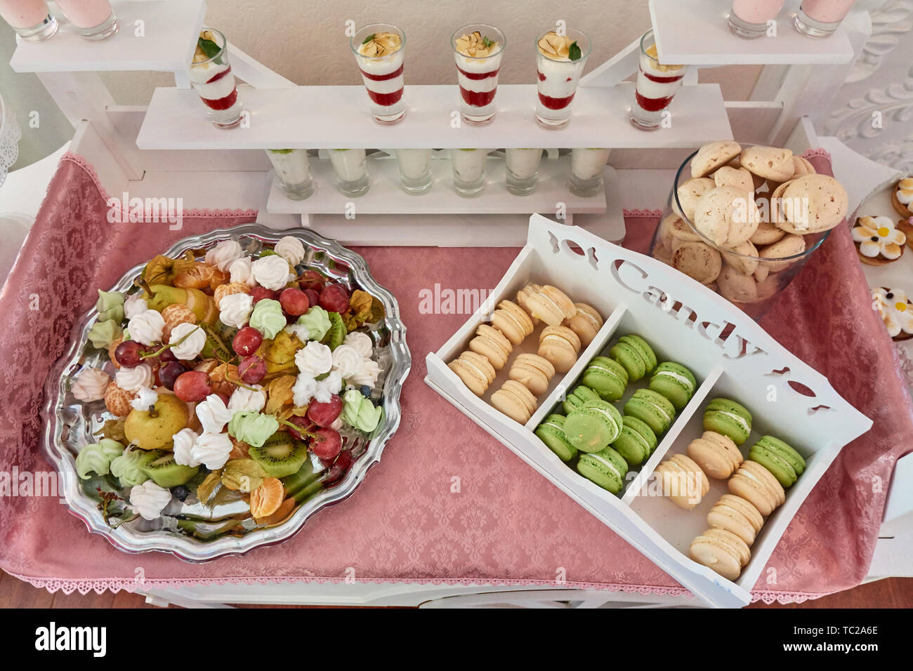 Candy bar splendidamente servito sul tavolo bianco con dolci, frutta, amaretti e altri dolci, matrimonio lusso assortimento Foto Stock