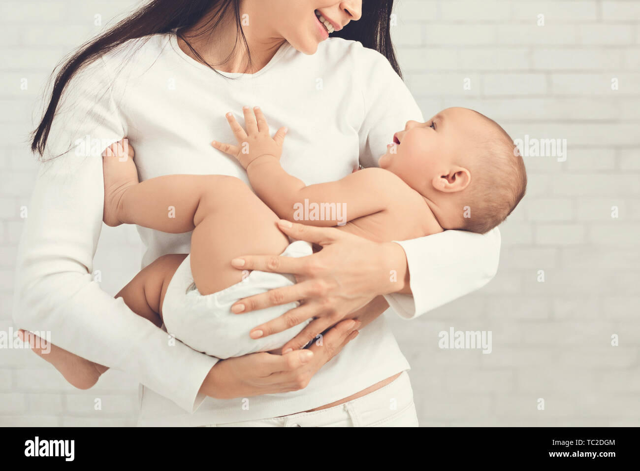 Giovane madre abbracciando il suo grazioso neonato Foto Stock