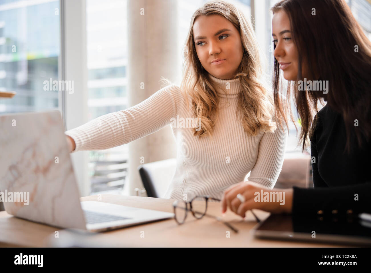 Due donne blogger discutendo su laptop a tavola in Cafe Foto Stock