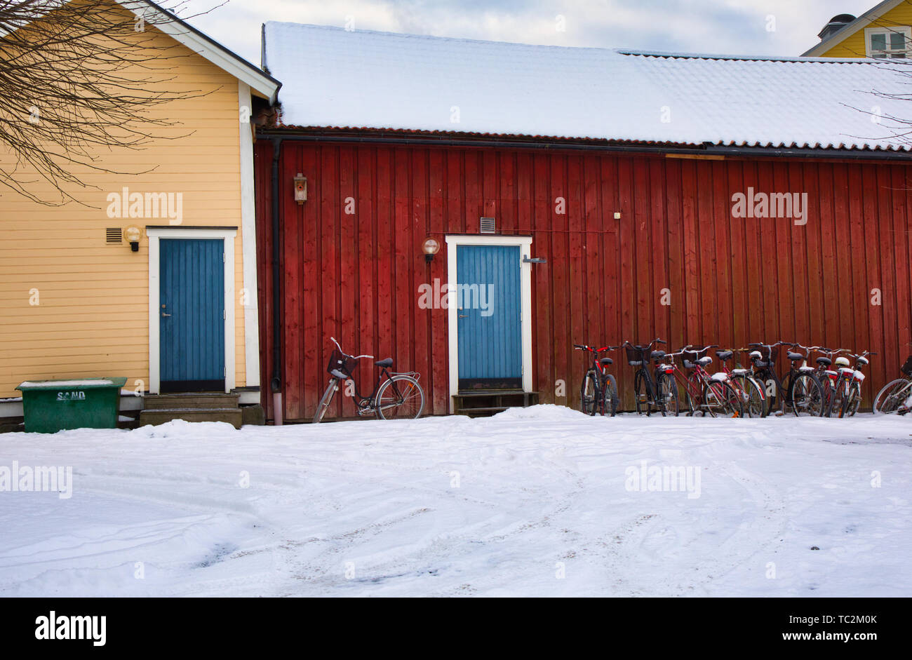 Le biciclette fuori dai tradizionali edifici in legno in inverno, Svezia e Scandinavia Foto Stock