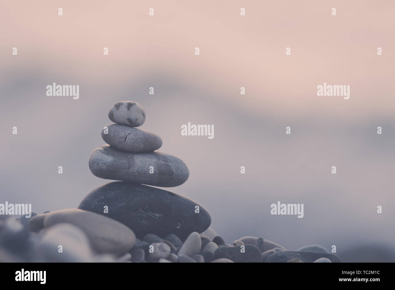 Piramide piegata Zen pietre ghiaia sul mare spiaggia al tramonto Foto Stock
