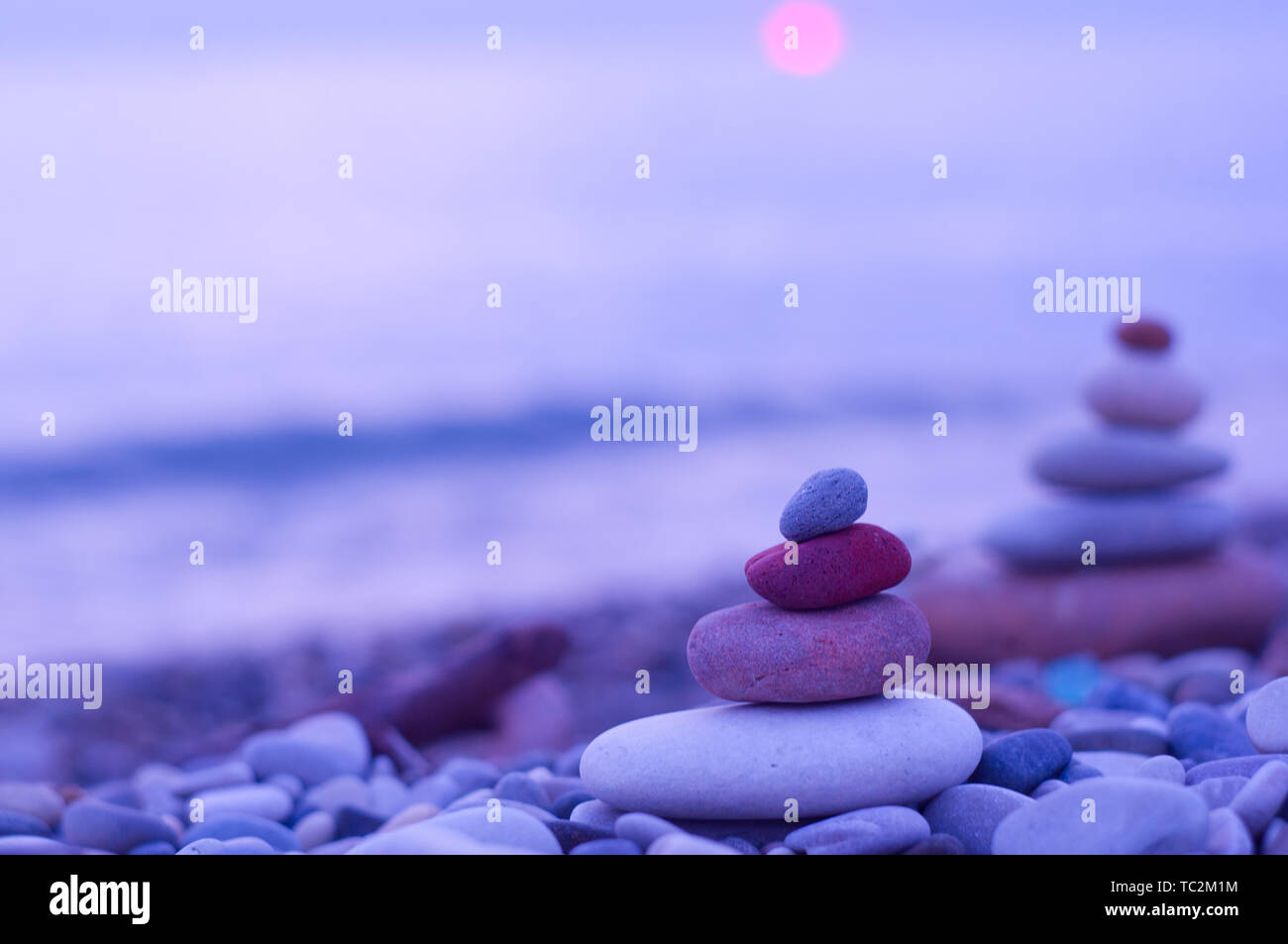 Piramide piegata Zen pietre ghiaia sul mare spiaggia al tramonto Foto Stock