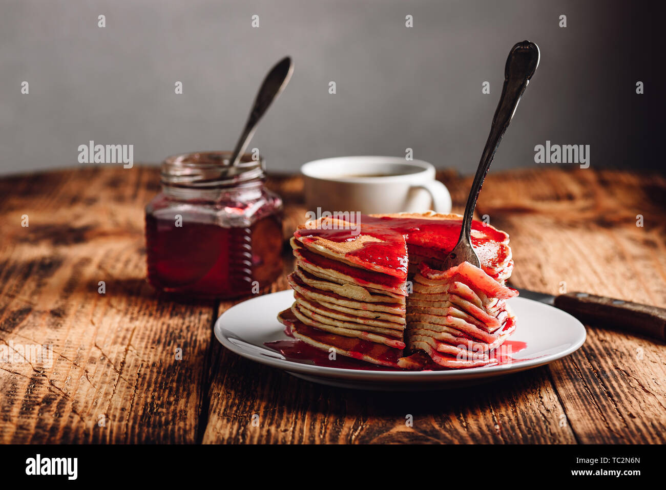 Pila di american pancake con red marmellata di frutti di bosco sulla piastra sulla superficie rustico Foto Stock