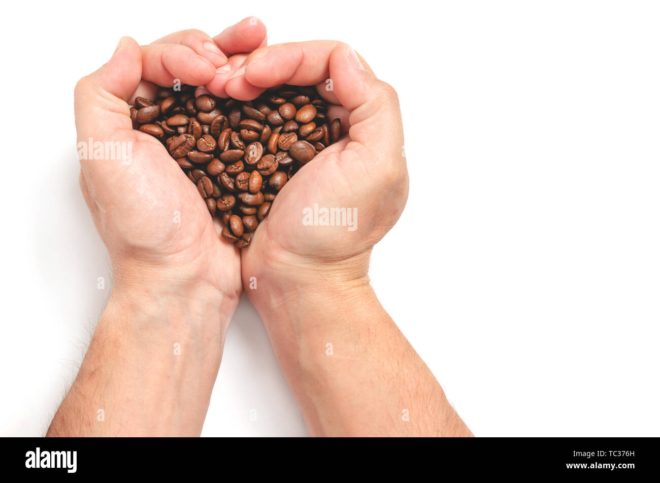 Gli uomini con le mani in mano tenere i chicchi di caffè formando una forma di cuore su uno sfondo bianco. Foto Stock