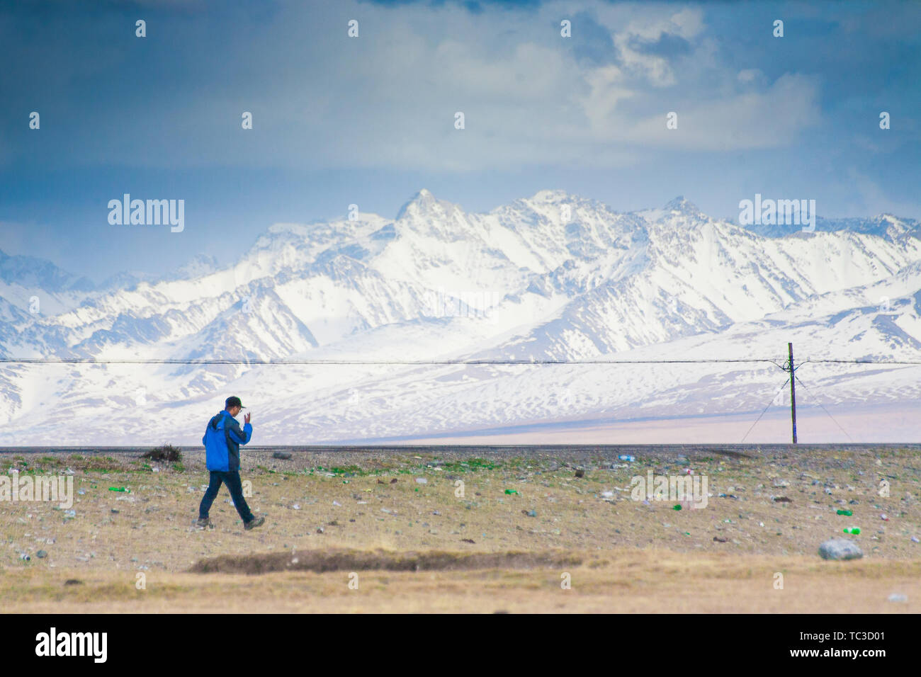 In primavera, un turista sta camminando sulla prateria Bayinbrook sezione dell'autostrada Doku. Lo sfondo è la Alte e maestose Tianshan picco di neve Foto Stock