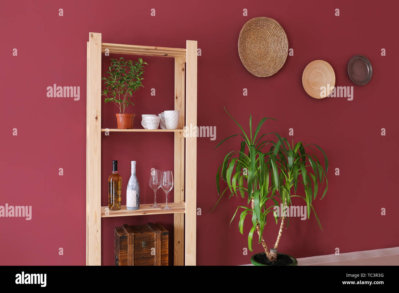 Rack con stoviglie e bottiglie di vino vicino a parete a colori in camera Foto Stock