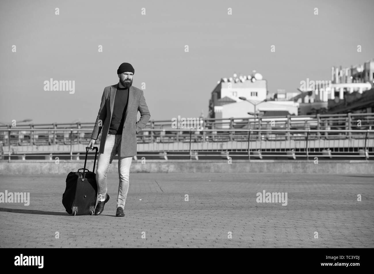 Viaggio di affari. Uomo Barbuto hipster viaggiare con grandi bagagli borsa su ruote. Lasciate che iniziano il viaggio. Viaggiatore con valigia arrivano alla stazione ferroviaria aeroportuale. Hipster pronto godetevi il viaggio. Portare una borsa da viaggio. Foto Stock