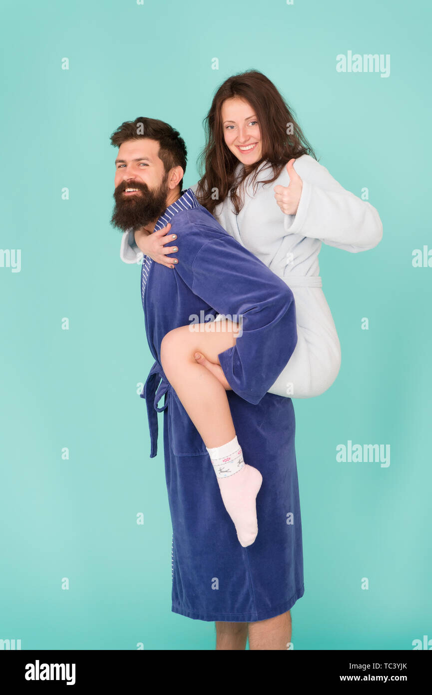 La fiducia e il supporto. Il vero amore. Consente di rimanere a casa. Essi sono gente più vicina. Il supporto in qualsiasi momento. Supporto affidabile. Bel giovane piggybacking bella donna. Matura in accappatoi avendo divertimento. Foto Stock