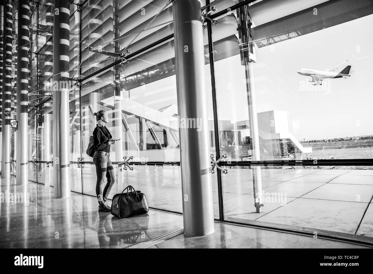 Giovane donna in attesa in aeroporto, guardando attraverso la finestra di gate. Foto Stock