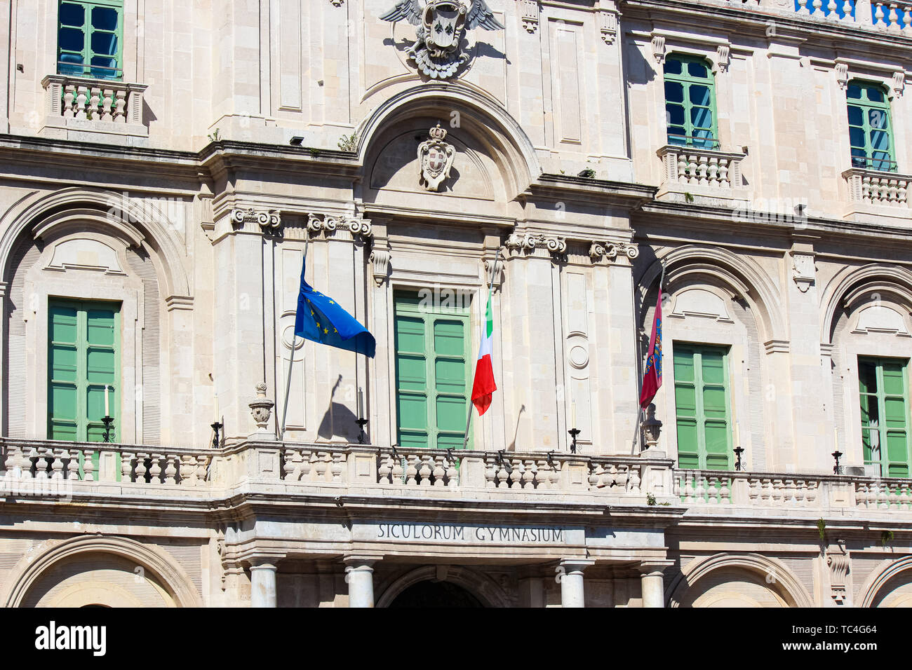 Close up foto cattura il lato anteriore facciata di edificio storico della Pubblica Università di Catania in Sicilia, Italia. Sul balcone ci sono sventola bandiera italiana e la bandiera dell'Unione europea. Foto Stock