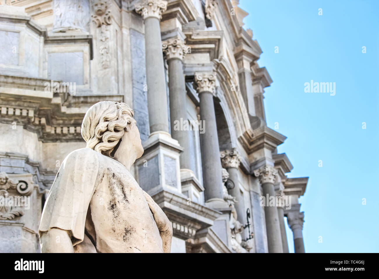 Bellissimo dettaglio della antica statua sul Duomo di Catania con Romano sfocata santuario Cattolico in background. Il Duomo barocco è una delle principali attrazioni turistiche di Catania, Sicilia, Italia. Foto Stock