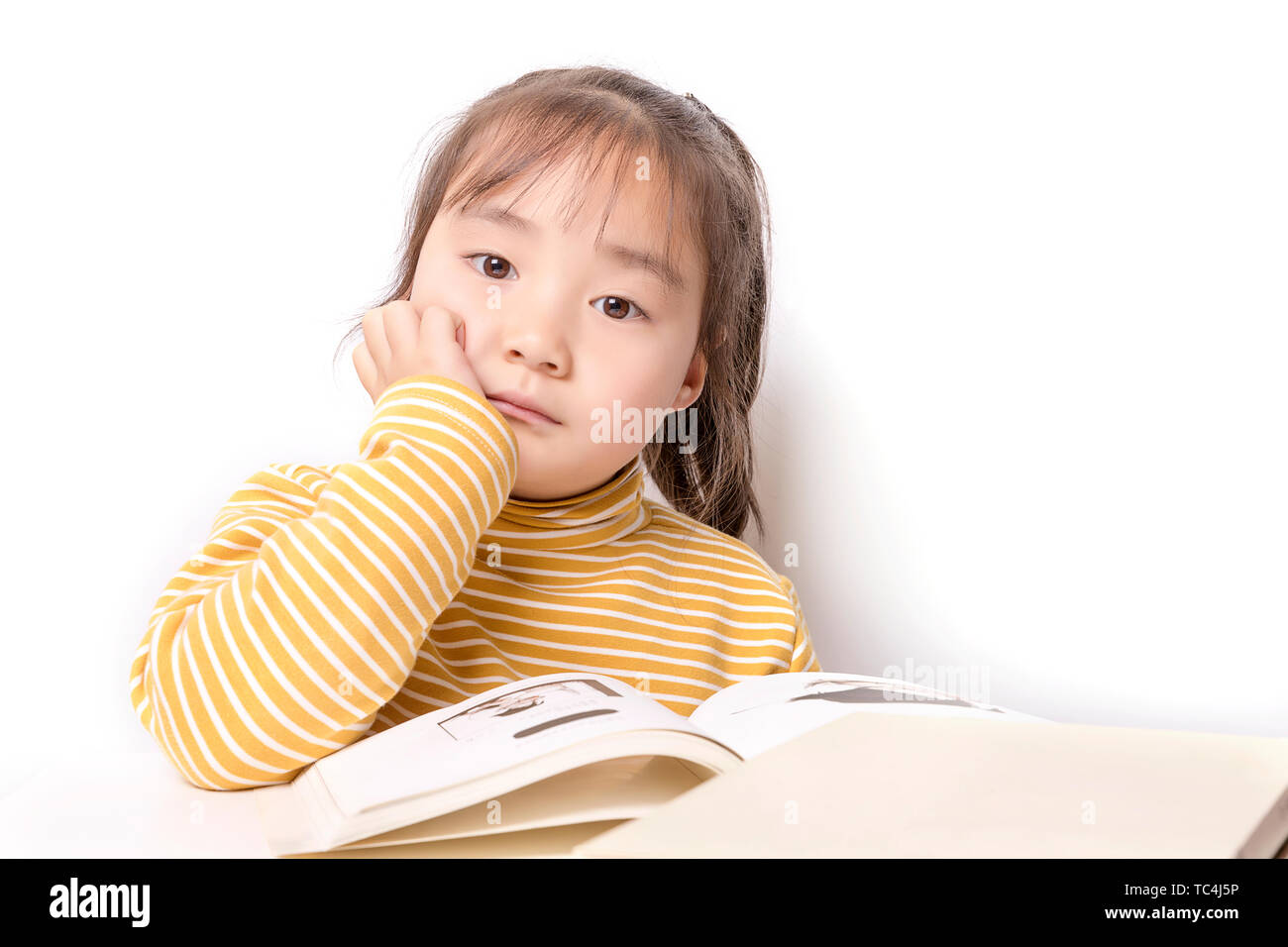 Carino asian bambina la lettura di un libro di fronte a uno sfondo bianco Foto Stock