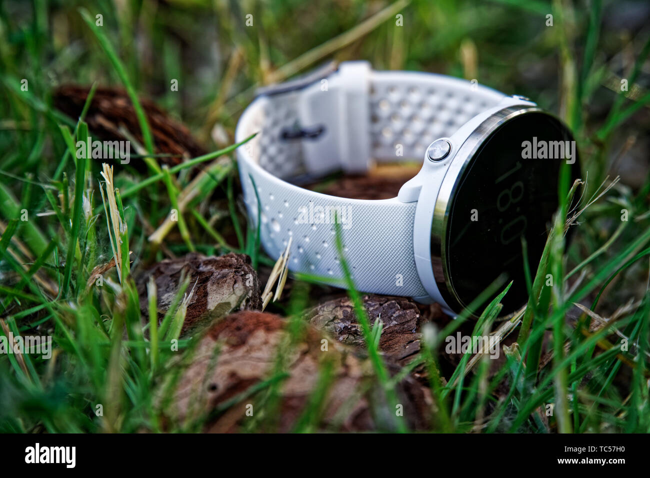 Sport watch per l'esecuzione di colore bianco sul terreno in erba. Orologio fitness per tenere traccia delle attività quotidiane e la forza di formazione Foto Stock