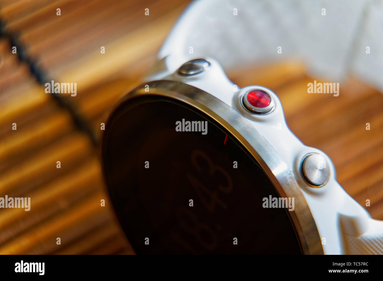 Orologio sportivo di colore bianco e rosso pulsante sul tavolo di legno, orologio intelligente per correre e allenamento di fitness Foto Stock