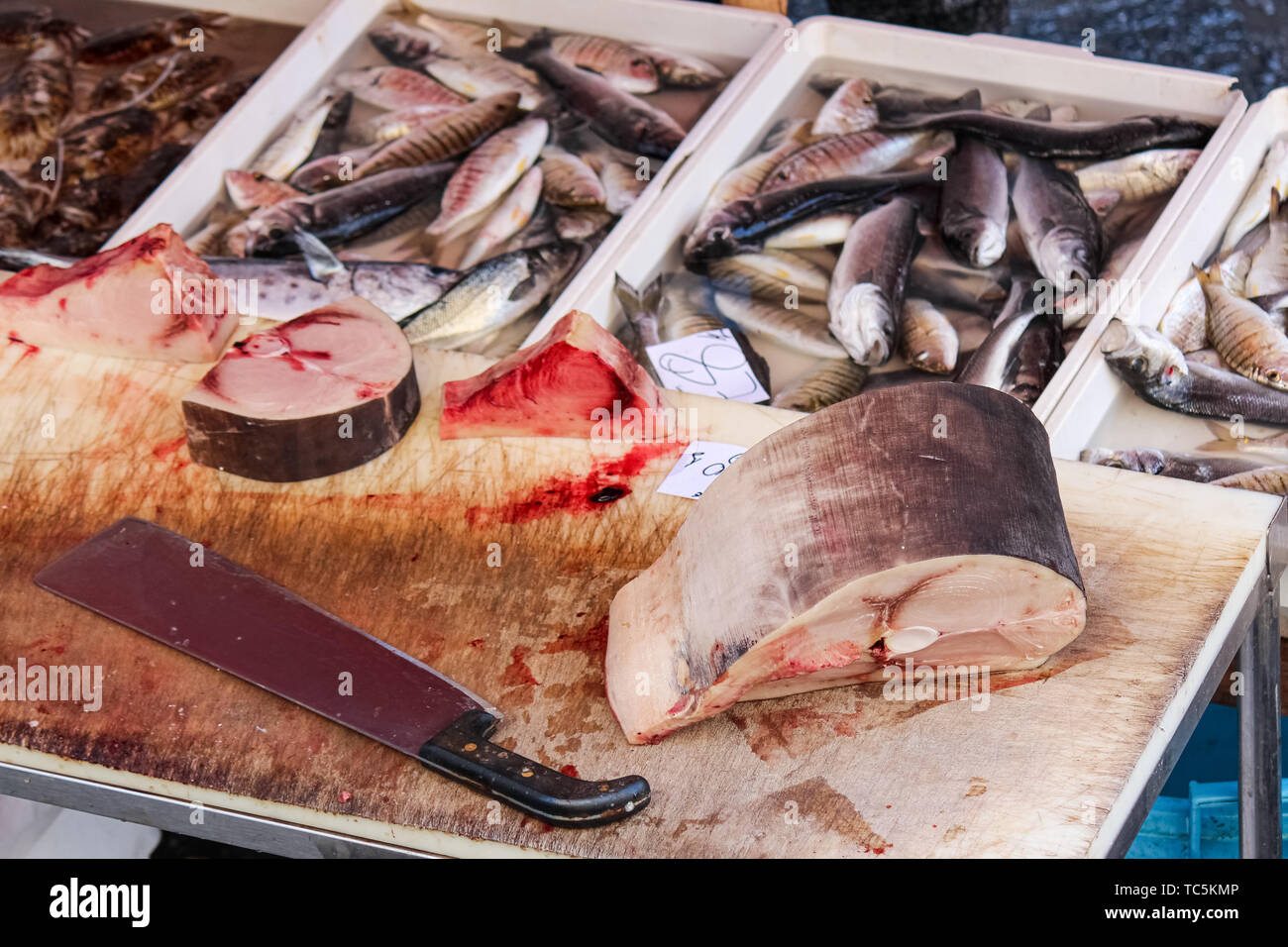 Dettaglio di fettine di pesce morto su un tavolo di legno con grandi cleaver. Altri pesci morti sfocati in background. Protezione animale concetto. La pesca di frodo, caccia illegale. Problema globale. Foto Stock