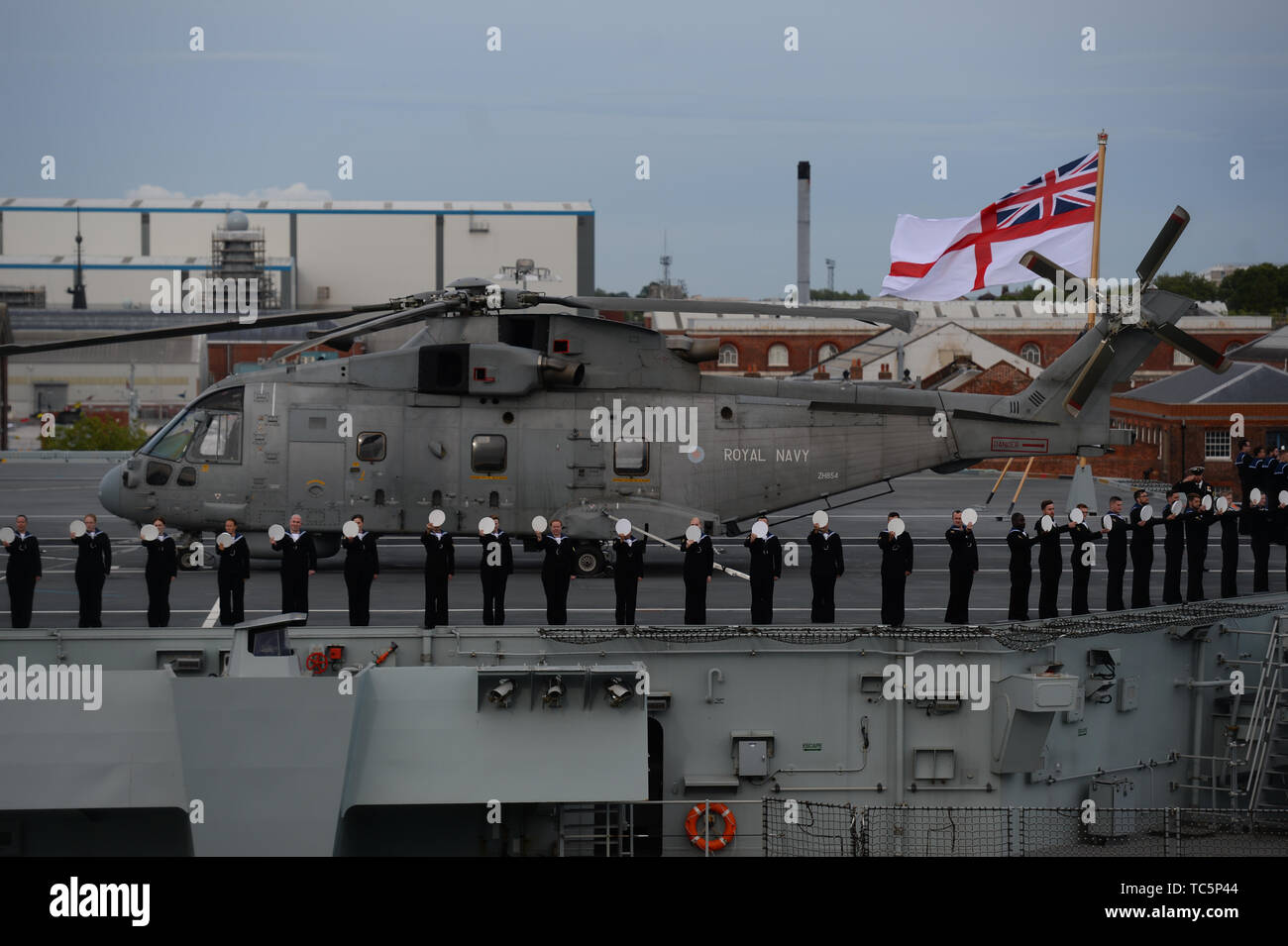 I membri della compagnia della nave supporto sul ponte della HMS Queen Elizabeth, come essi allietare off veterani a bordo della MV Boudicca vela al di fuori del porto di Portsmouth per lui il porto di Le Havre in Francia come parte delle commemorazioni per il settantacinquesimo anniversario dello sbarco in Normandia. Foto Stock