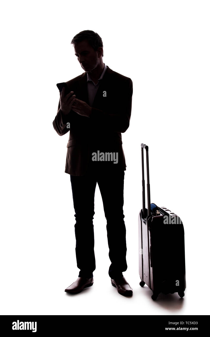 Silhouette di un imprenditore che è chiamata per un rideshare con un cellulare. Egli è in attesa con i suoi bagagli se arrivate da un aeroporto. Isolato Foto Stock