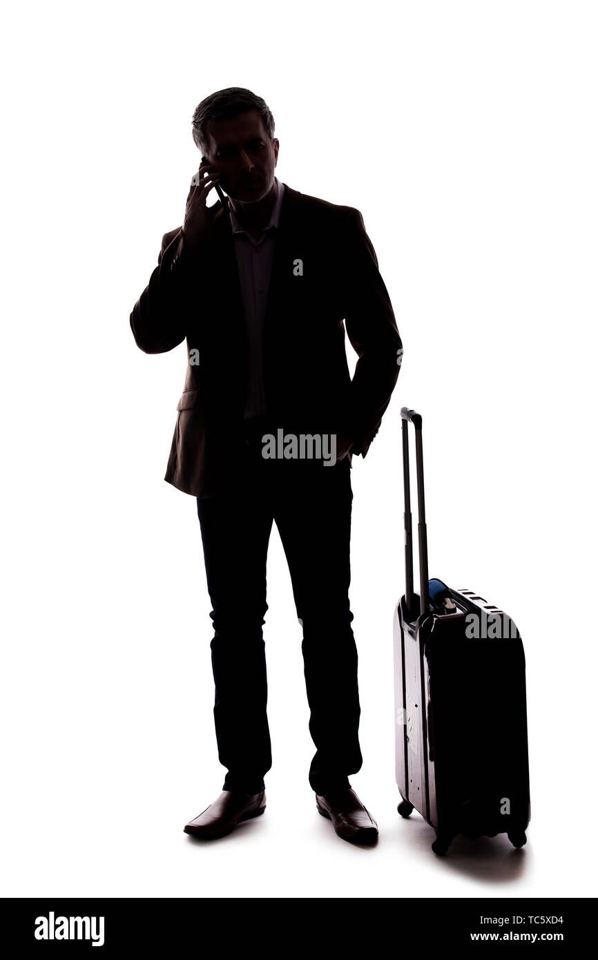 Silhouette di un imprenditore che è chiamata per un rideshare con un cellulare. Egli è in attesa con i suoi bagagli se arrivate da un aeroporto. Isolato Foto Stock