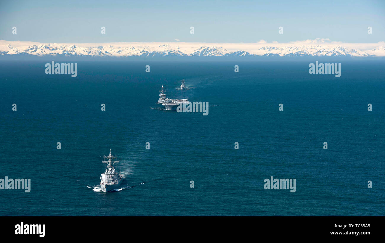 Gli Stati Uniti Nimitz Navy-class nuclear powered portaerei USS Theodore Roosevelt è scortato dal Arleigh Burke-class guidato-missile destroyer USS Russel, anteriore e il Arleigh Burke-class guidato-missile destroyer USS John Finn, posteriore, durante l'esercizio bordo settentrionale 2019 Maggio 24, 2019 nel Golfo di Alaska. Foto Stock