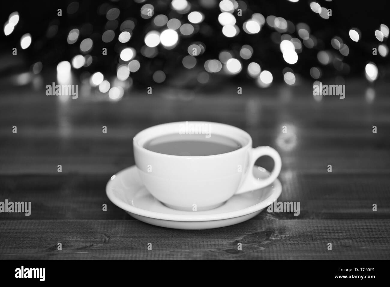 Bere un caffè la mattina di natale. Tempo di caffè della vigilia di Natale. Caffe' macinato di fresco in bianco tazza o tazza alta sulla ghirlanda sfocati sullo sfondo delle luci. Bere caffè inverno vacanze anno nuovo. Foto Stock