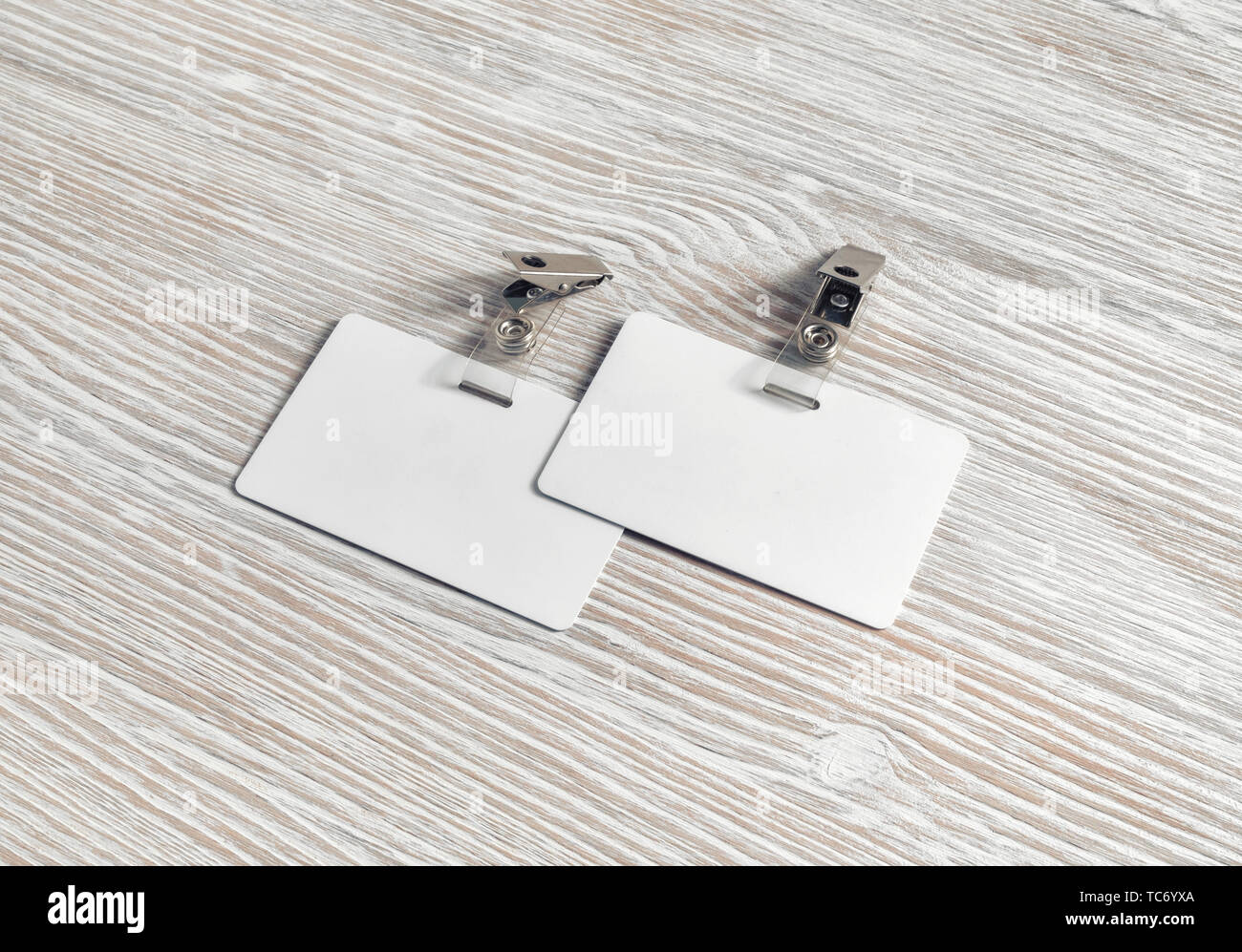 Blank badge in plastica sul legno chiaro sfondo tabella. Spazio per il testo. Bianco di schede ID. Foto Stock