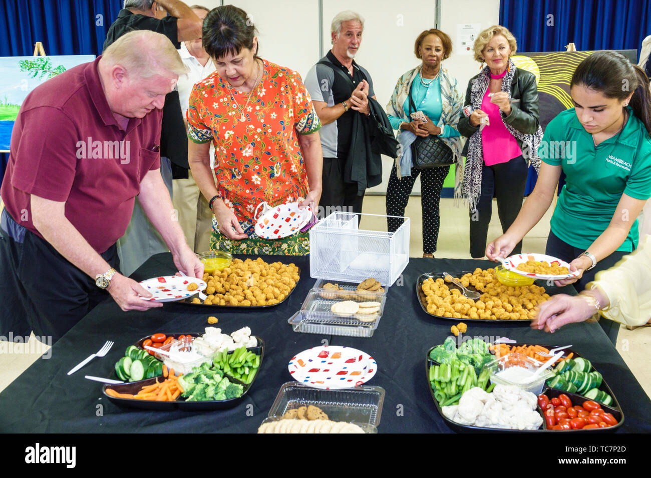 Miami Beach Florida, North Beach, North Shore Park & Youth Center, anziani cittadini, spettacolo di classe d'arte, cibo, tavolo a buffet, uomo maschio, donna fe Foto Stock