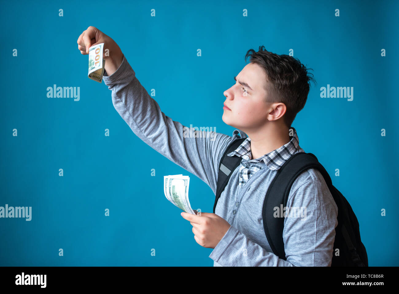 Cash loan, primo denaro facile e spendere soldi. Ragazzo adolescente tiene in mano il denaro e gli assegni vera o falsa fatture. Gli utili o le vincite online. Foto Stock