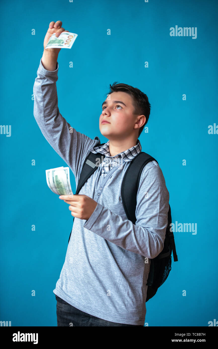 Cash loan, primo denaro facile e spendere soldi. Ragazzo adolescente tiene in mano il denaro e gli assegni vera o falsa fatture. Gli utili o le vincite online. Foto Stock