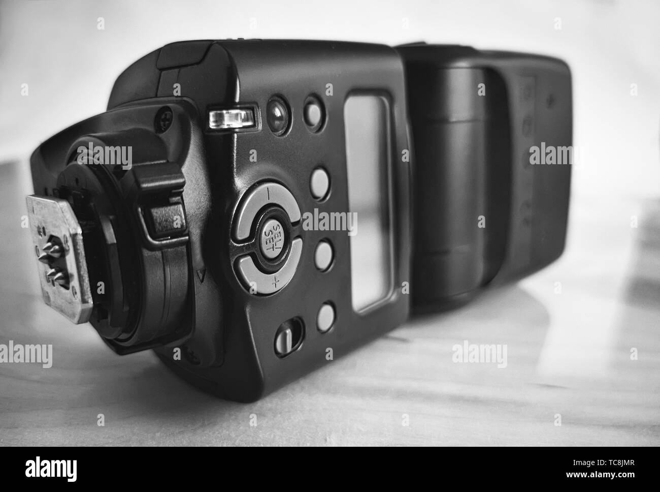 Close-up è un moderno flash per una fotocamera reflex per una migliore illuminazione durante le riprese. Immagine in bianco e nero. Foto Stock