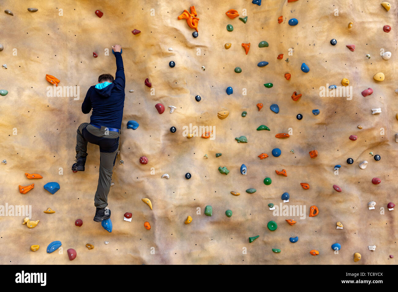 Bouldering - uomo arrampicata su roccia artificiale parete Foto Stock