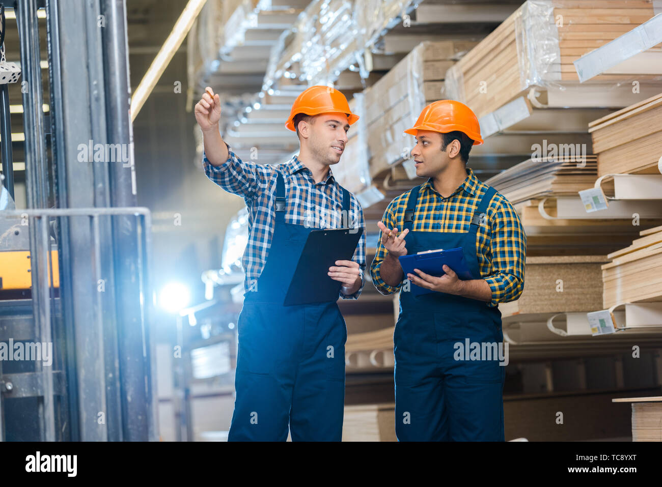 Lavoratore sorridente rivolta con la matita mentre si parla al collega indiano Foto Stock