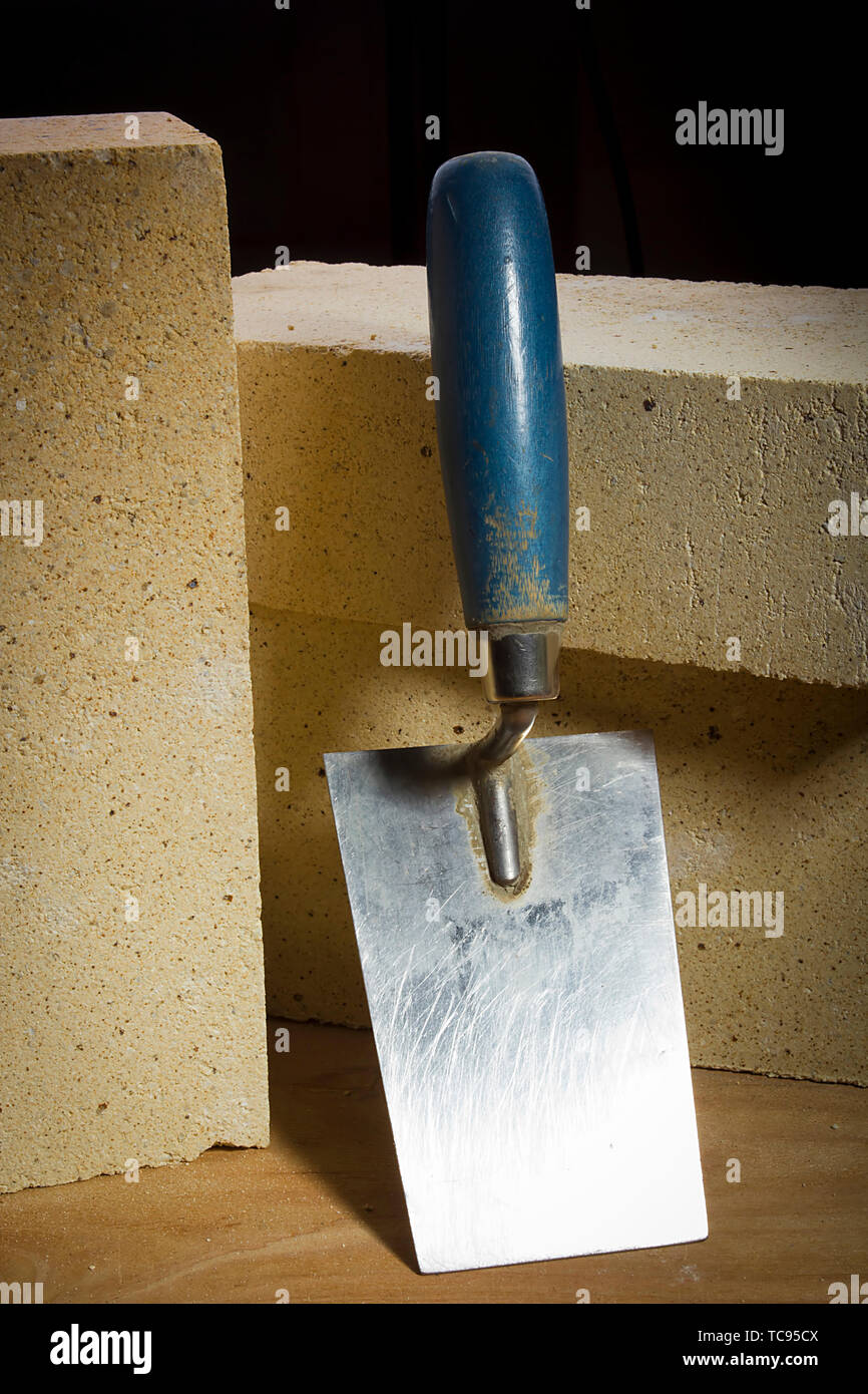 Fire mattoni e frattazzo su una superficie in legno Foto Stock