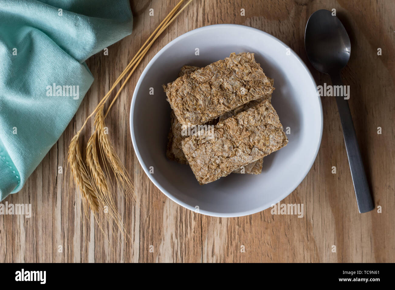Cereali frumento nella ciotola con i germogli di grano sul tavolo di legno con cucchiaio e tovagliolo - top view foto Foto Stock