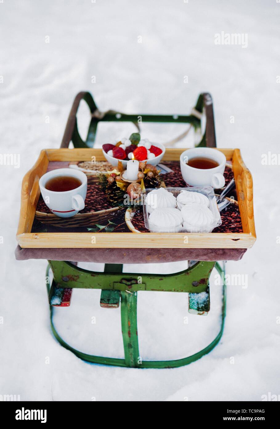 Colazione romantica nella neve. Invernali slittino Vintage. Caffè, marshmallows e altri dolci in un vano con una candela che brucia. Foto Stock