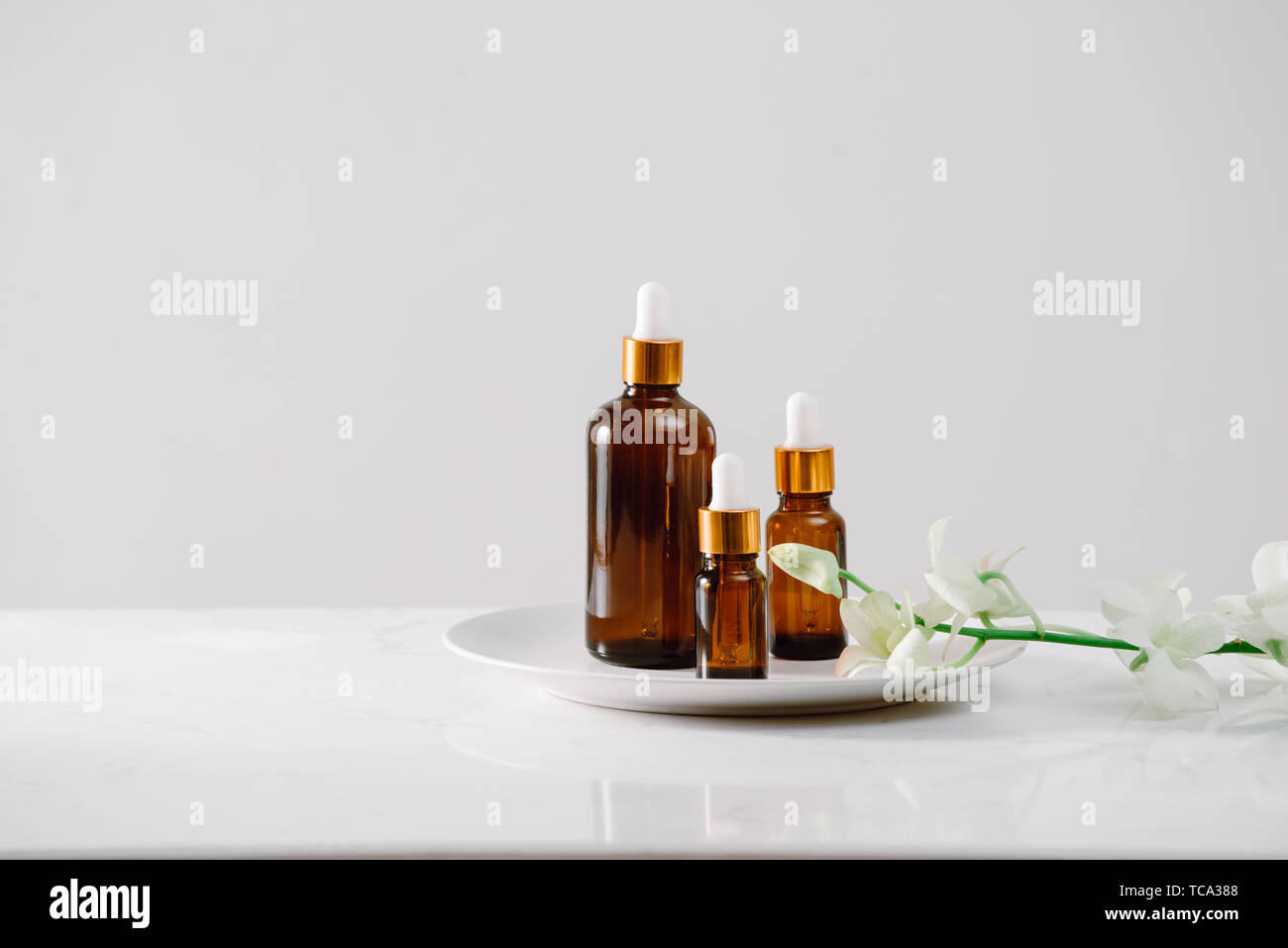 Impostazione di Spa con orchidee e olio essenziale in una bottiglia di vetro, aromaterapia concept Foto Stock