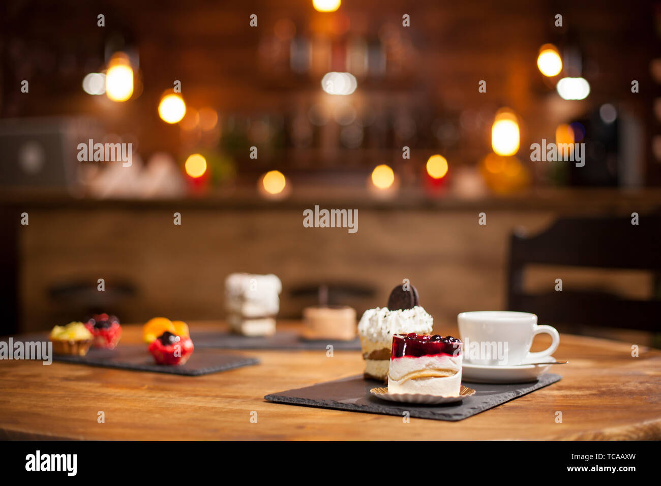 Composizione di diverse torte con gustosi sapori su una tavola di legno in una caffetteria. Mini gustose torte alla frutta. Torte con deliziosi biscotti sulla parte superiore. Foto Stock