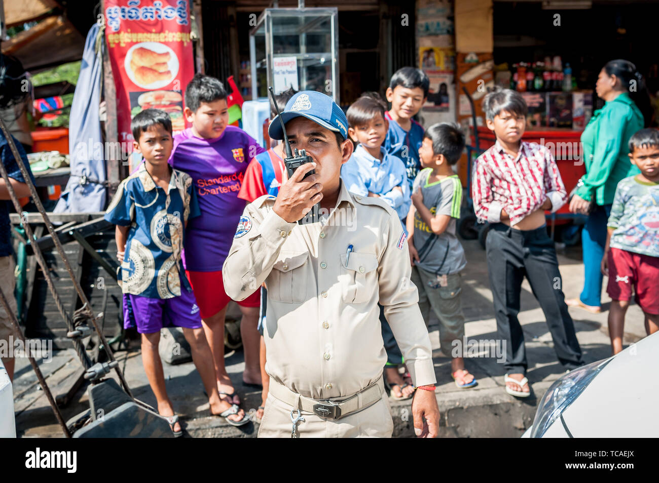 Un poliziotto cambogiano circondato da bambini di strada assiste ad una situazione in Cambogia la città di Phnom Penh. Foto Stock