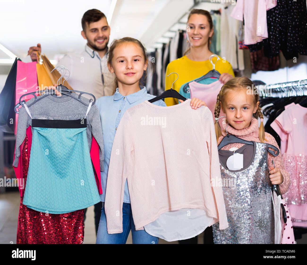 Ritratto di due felice allegro sorriso positivo bambine e i loro genitori con nuovi vestiti nel centro commerciale per lo shopping Foto Stock