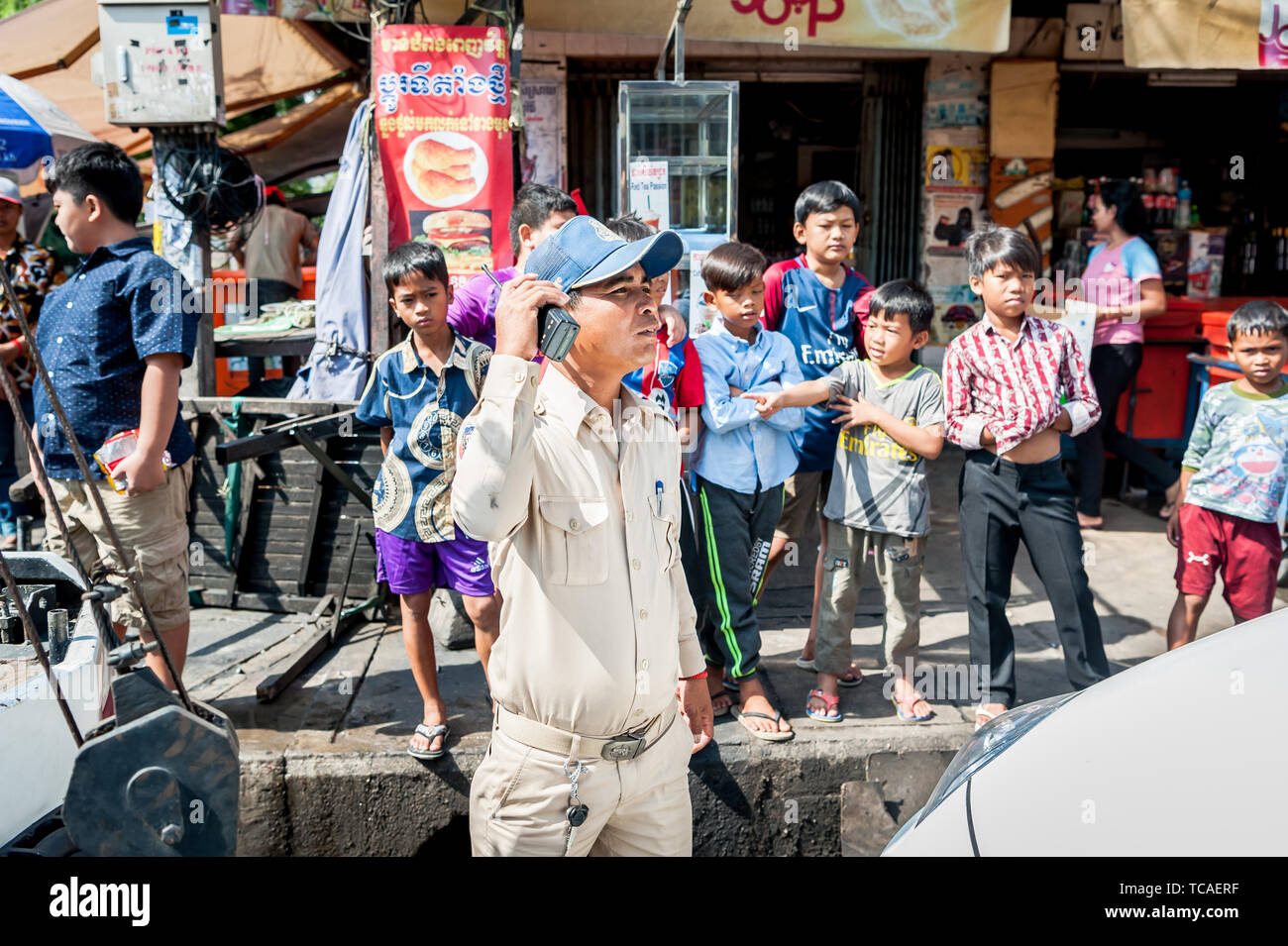 Un poliziotto cambogiano circondato da bambini di strada assiste ad una situazione in Cambogia la città di Phnom Penh. Foto Stock