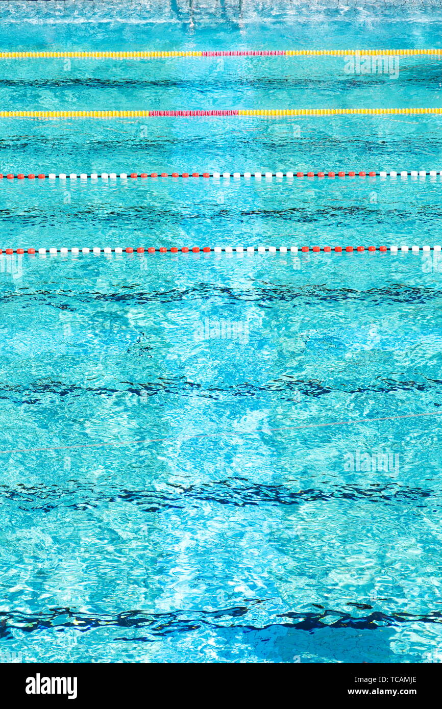 Il bianco e il rosso di corsie di nuoto nelle bellissime acque azzurre, vuoto piscina esterna, estate giornata soleggiata, copia spazio, vista aerea Foto Stock